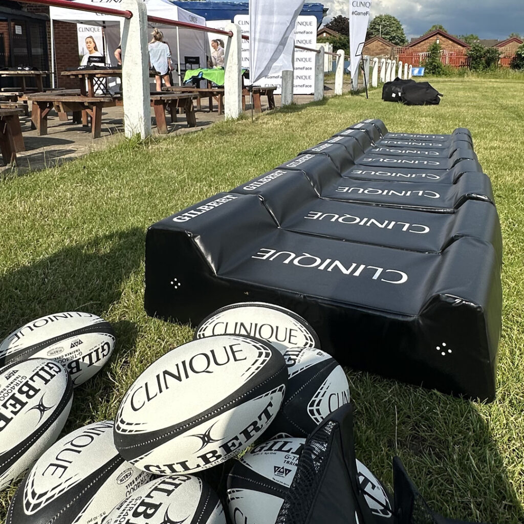 Clinique branded rugby balls and crash pads laid out on rugby pitch