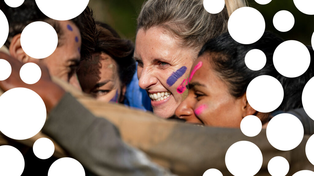 Female smiling with blue paint on her face and Race for Life spot branding overlayed