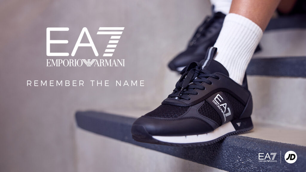 A close up of a black EA7 trainer on a woman’s foot in an industrial stairwell, with the EA7 logo overlaid along with the headline REMEMBER THE NAME