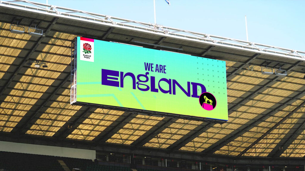 In-situ screen in a stadium showing the England Rugby This Rose Means Everything campaign - a blue and green background with purple text saying WE ARE ENGLAND with the England Rugby logo