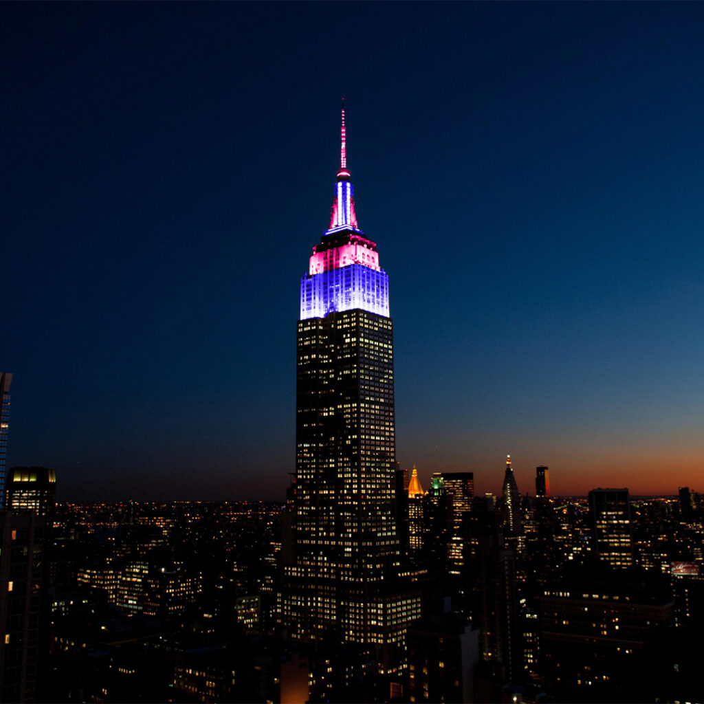 Empire State building lit up in ICC T20 brand colours, pink and blue in New York City