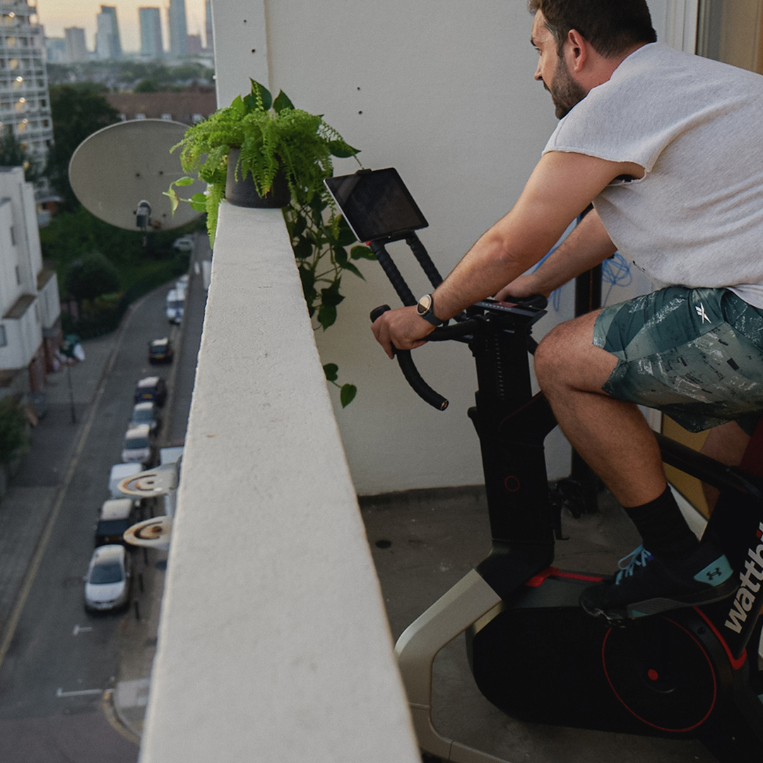 A man completing a Wattbike session on the balcony of his inner-city apartment.