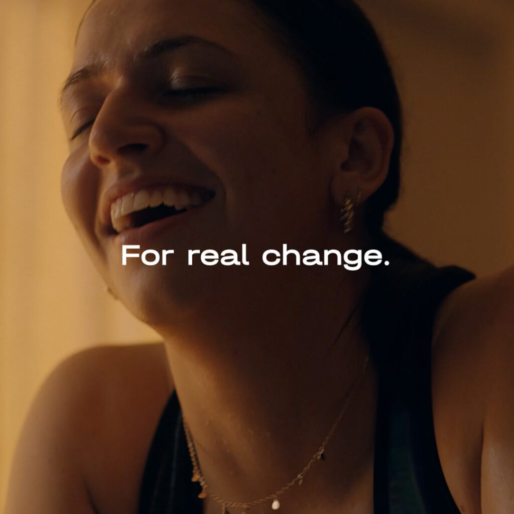 Woman smiling after an intense workout on her Wattbike, with the title: “For real change”.