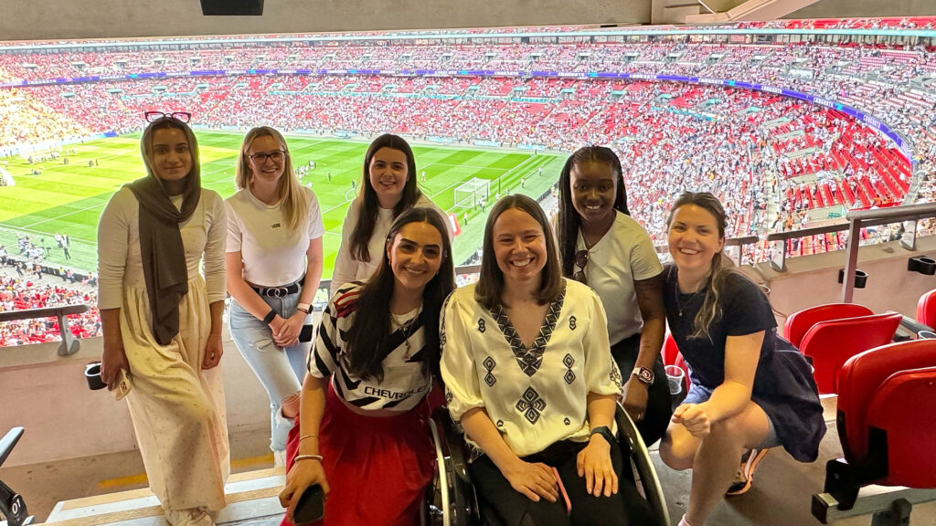 Group of women from MATTA and young girls in front of the pitch at Wembley at the Women's FA Cup Final